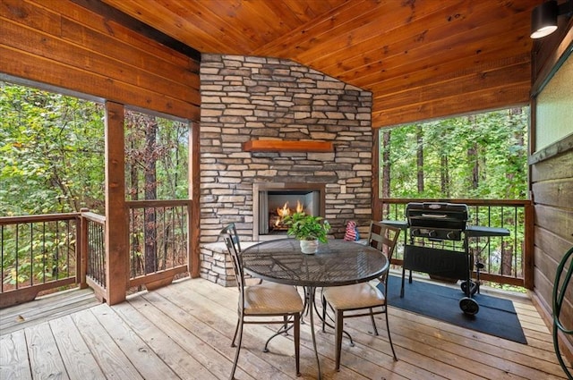 unfurnished sunroom featuring plenty of natural light, an outdoor stone fireplace, wooden ceiling, and vaulted ceiling