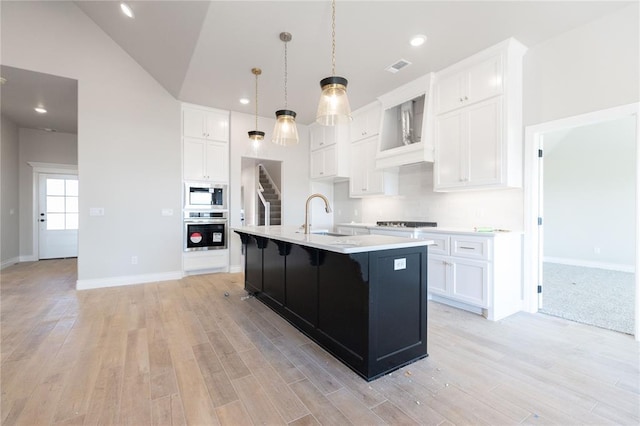 kitchen with light wood finished floors, stainless steel appliances, a sink, and light countertops