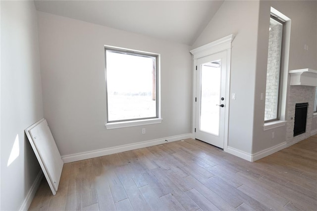 interior space featuring lofted ceiling, a fireplace, wood finished floors, and baseboards