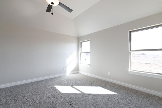 carpeted empty room with lofted ceiling, baseboards, and a ceiling fan