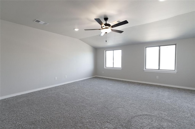 carpeted empty room featuring lofted ceiling, ceiling fan, visible vents, and baseboards