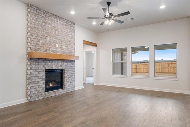 unfurnished living room featuring ceiling fan, hardwood / wood-style floors, and a brick fireplace