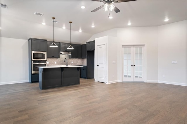 kitchen with french doors, stainless steel appliances, dark hardwood / wood-style floors, an island with sink, and pendant lighting