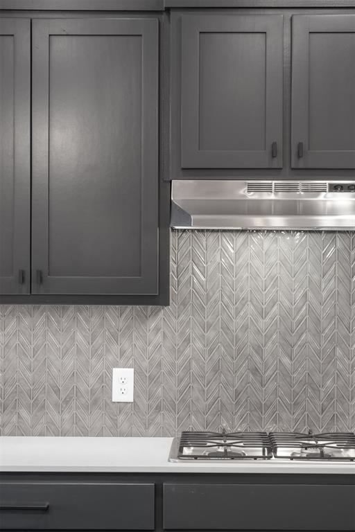 interior space with stainless steel gas stovetop, wall chimney range hood, and tasteful backsplash