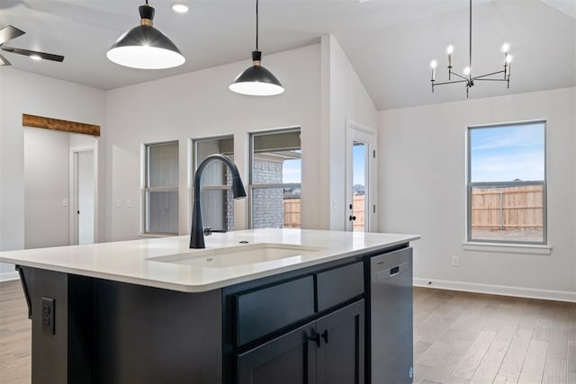 kitchen with stainless steel dishwasher, light hardwood / wood-style floors, sink, and an island with sink