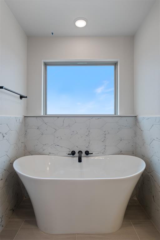 bathroom with tile patterned floors, a bathtub, and tile walls