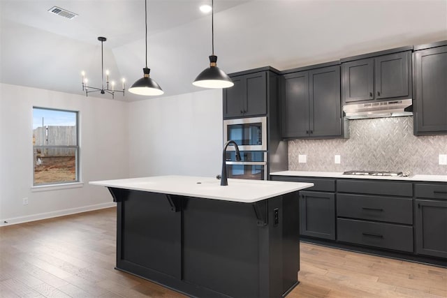 590 Emmy Jean Dr, Blanchard, OK 73010 - kitchen featuring stainless steel appliances, under cabinet range hood, tasteful backsplash, light countertops, and vaulted ceiling