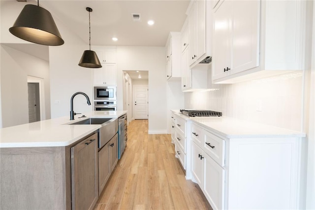 kitchen featuring backsplash, stainless steel appliances, a sink, and light countertops