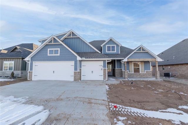 craftsman inspired home with central air condition unit, a garage, a shingled roof, driveway, and board and batten siding