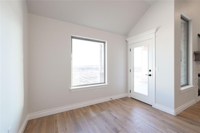 foyer entrance with a healthy amount of sunlight, light wood-style flooring, baseboards, and vaulted ceiling