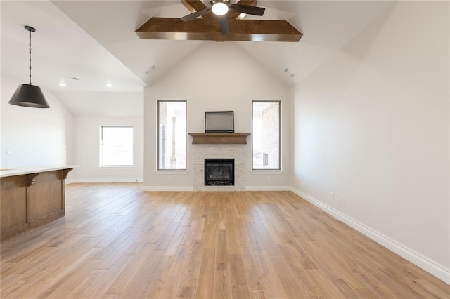 unfurnished living room with light wood-style floors, ceiling fan, baseboards, and a stone fireplace