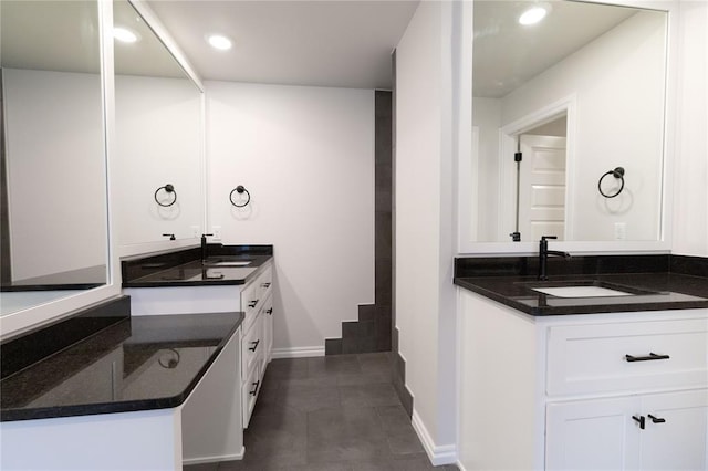 bathroom featuring two vanities, a sink, and baseboards