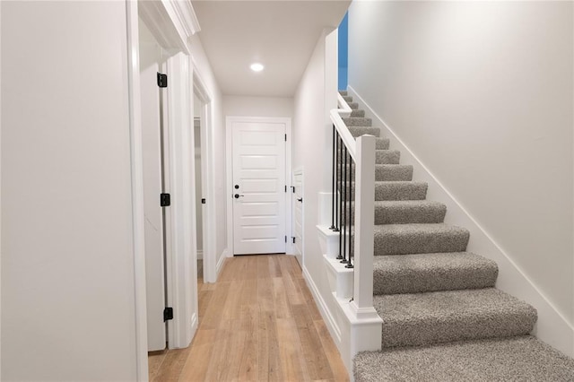 stairway with wood finished floors and recessed lighting