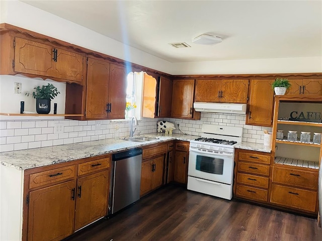 kitchen with under cabinet range hood, a sink, white range with gas cooktop, stainless steel dishwasher, and brown cabinetry