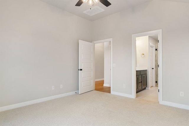 unfurnished bedroom featuring ceiling fan, light colored carpet, and ensuite bathroom