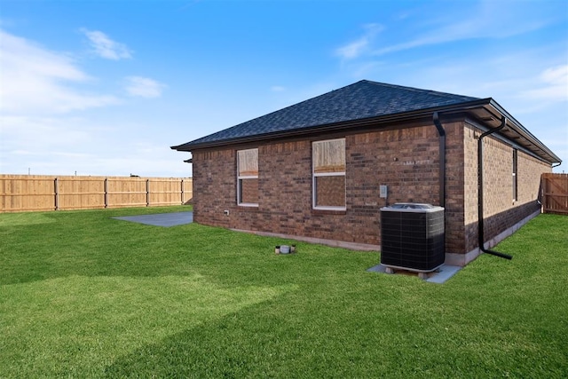 view of side of home with a patio, a yard, and central AC