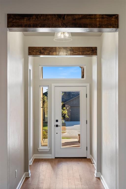 doorway with beamed ceiling and light wood-type flooring