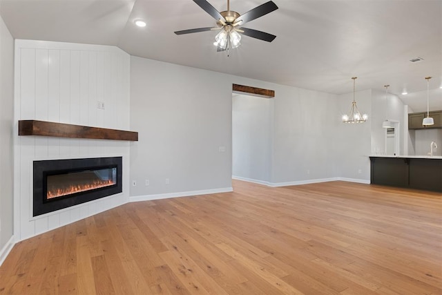 unfurnished living room featuring ceiling fan with notable chandelier, light hardwood / wood-style floors, lofted ceiling, and sink