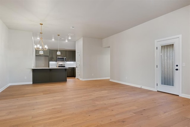 kitchen featuring pendant lighting, light hardwood / wood-style floors, appliances with stainless steel finishes, and a chandelier