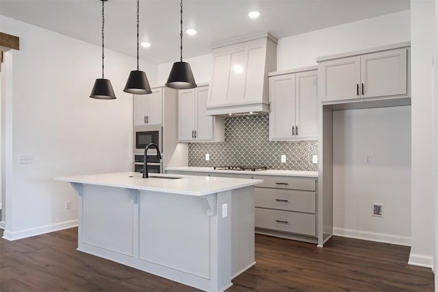 kitchen featuring decorative light fixtures, dark hardwood / wood-style floors, an island with sink, and black microwave