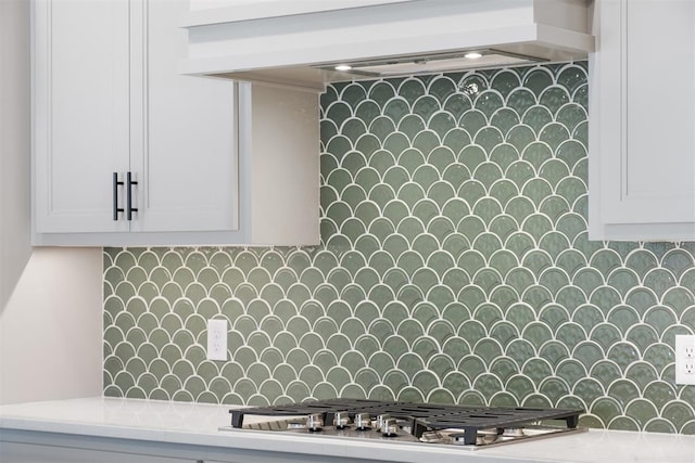 interior space with white cabinets, custom range hood, tasteful backsplash, and stainless steel gas cooktop