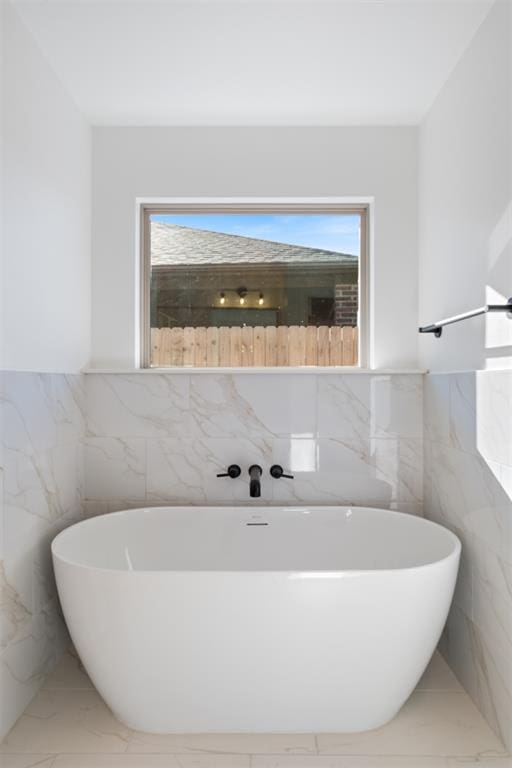 bathroom featuring a washtub and tile walls