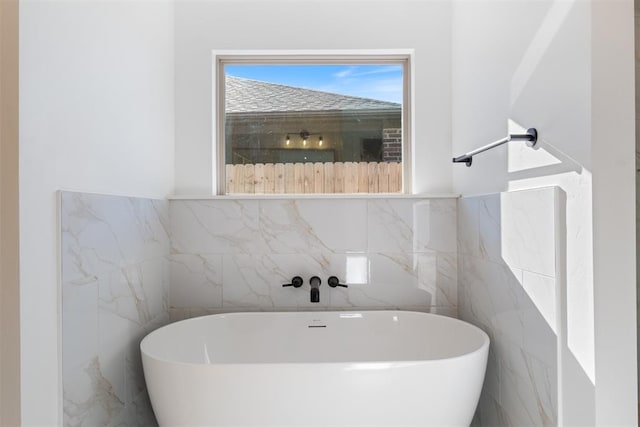 bathroom featuring a bathtub and tile walls