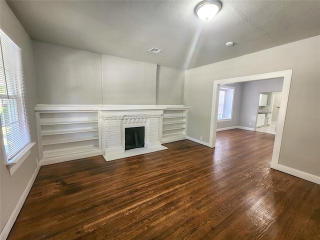 unfurnished living room featuring a textured ceiling, a fireplace, and dark hardwood / wood-style floors