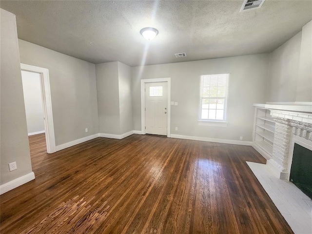 unfurnished living room with a fireplace, dark wood-type flooring, and a textured ceiling