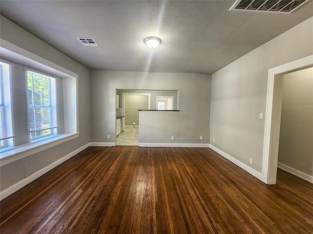 spare room with a textured ceiling and dark wood-type flooring