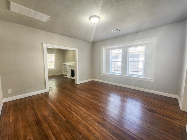 unfurnished living room with a textured ceiling and dark wood-type flooring