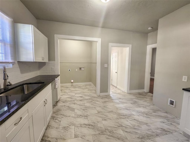 kitchen with backsplash, dark stone counters, a textured ceiling, sink, and white cabinetry