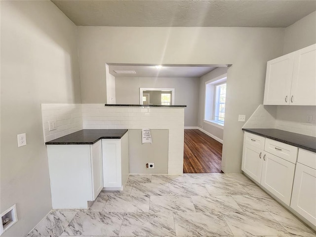 kitchen with white cabinets, backsplash, light hardwood / wood-style floors, and kitchen peninsula