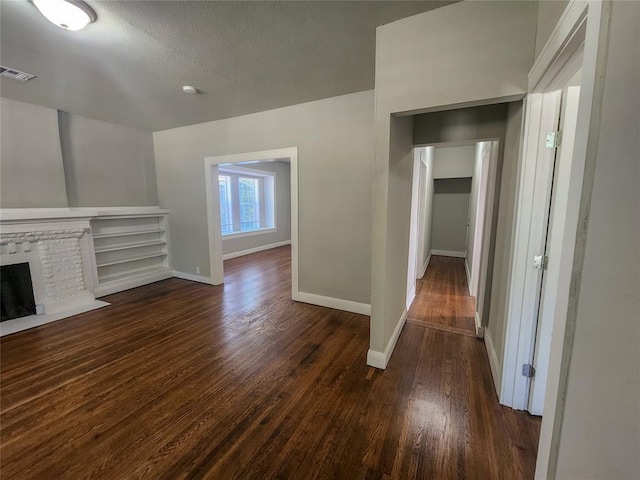 unfurnished living room with a textured ceiling, a fireplace, and dark wood-type flooring