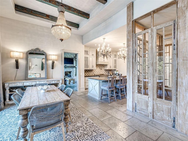 dining room with a fireplace, beam ceiling, and a notable chandelier