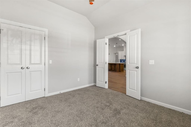 unfurnished bedroom with lofted ceiling, carpet floors, and a closet