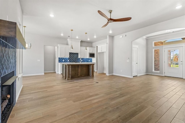 unfurnished living room featuring light wood-type flooring, ceiling fan, and sink