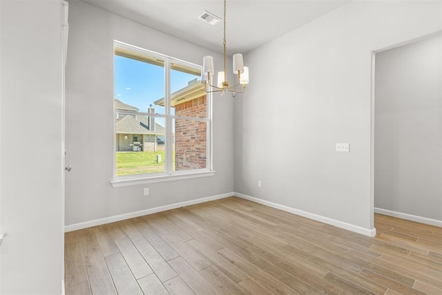 empty room with a notable chandelier and light wood-type flooring