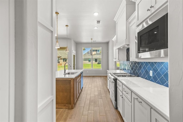 kitchen featuring white cabinets, stainless steel appliances, light stone counters, and sink