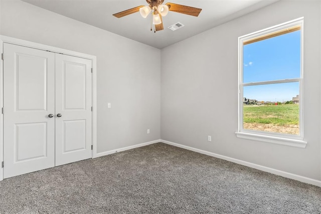 empty room with carpet flooring, a wealth of natural light, and ceiling fan