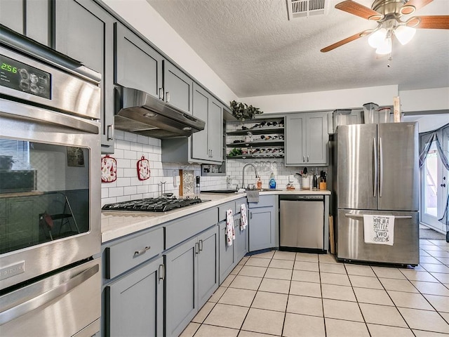 kitchen featuring tasteful backsplash, gray cabinets, ceiling fan, and stainless steel appliances