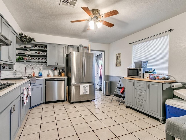 kitchen with gray cabinets, ceiling fan, a healthy amount of sunlight, and appliances with stainless steel finishes