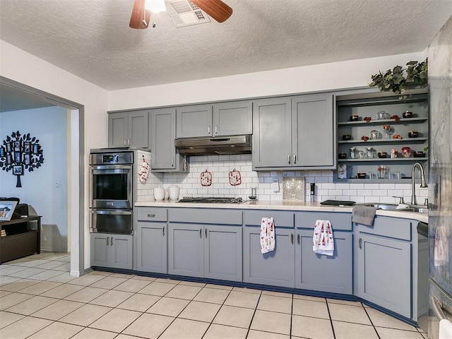 kitchen featuring decorative backsplash, ceiling fan, light tile patterned floors, and appliances with stainless steel finishes