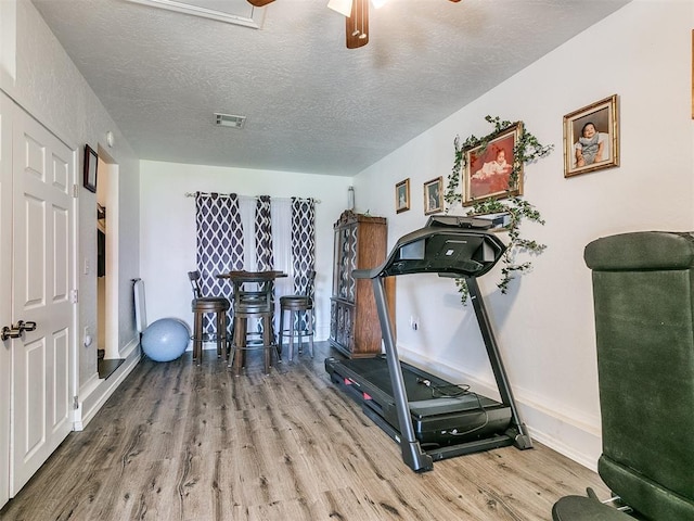 exercise area with hardwood / wood-style flooring, ceiling fan, and a textured ceiling