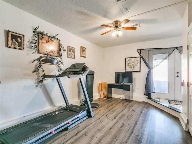 exercise area with ceiling fan, wood-type flooring, and a textured ceiling