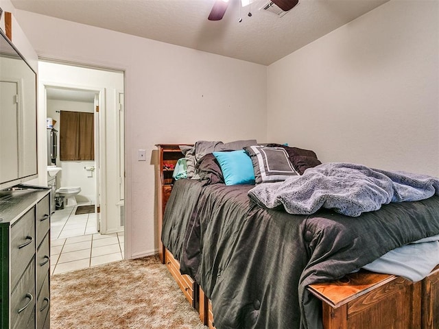 bedroom with ensuite bathroom, ceiling fan, and light colored carpet