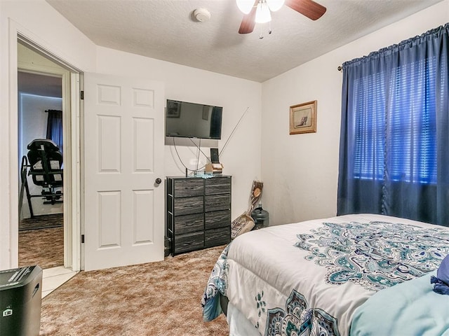 carpeted bedroom featuring ceiling fan and a textured ceiling