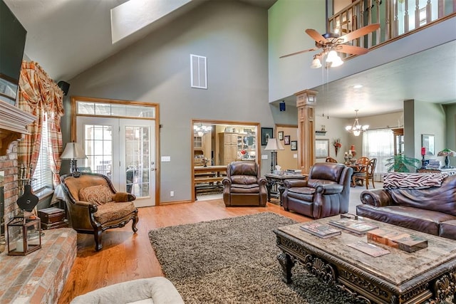 living room with high vaulted ceiling, light hardwood / wood-style floors, ceiling fan with notable chandelier, and a wealth of natural light