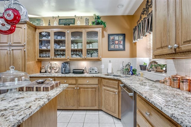 kitchen with light stone countertops, sink, stainless steel dishwasher, decorative backsplash, and light tile patterned flooring