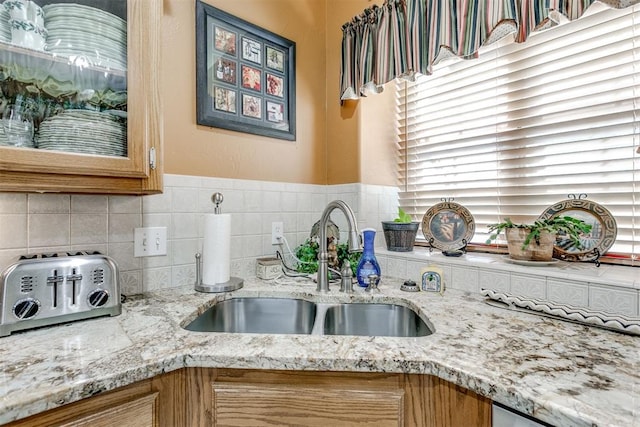 kitchen featuring tasteful backsplash, light stone counters, and sink